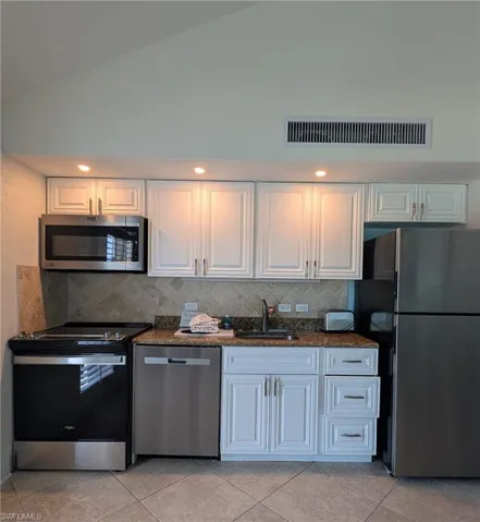 Kitchen with tasteful backsplash, visible vents, a sink, appliances with stainless steel finishes, and dark stone counters