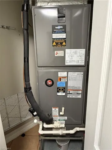 Gray central HVAC unit featuring insulated lines and white PVC piping