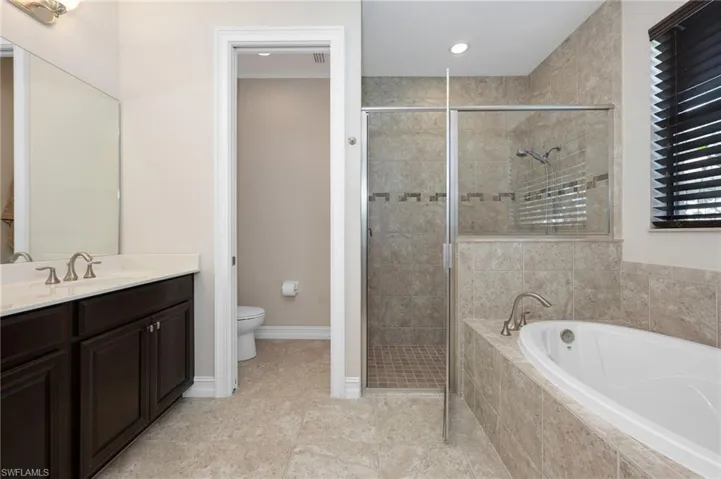 Master bathroom with vanity, plus walk in shower, toilet, and tile patterned floors