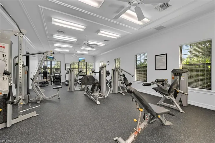 Workout area with ceiling fan and crown molding