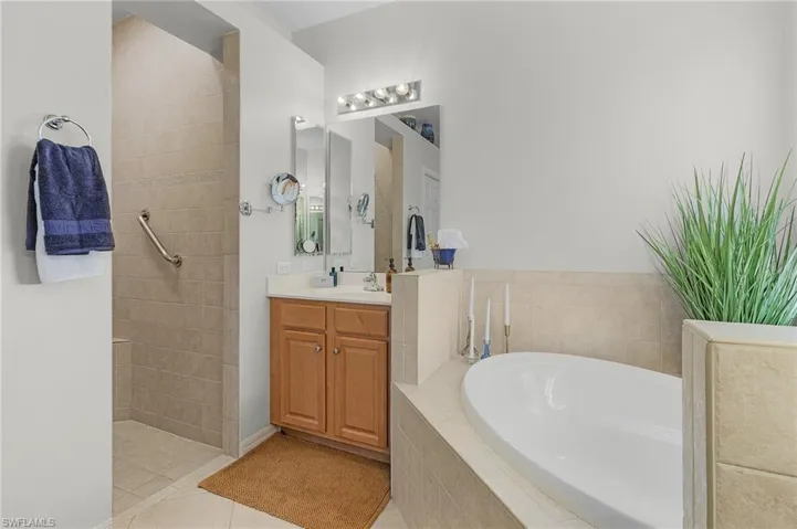 Bathroom with vanity, tiled tub, tile patterned floors, and ceiling fan