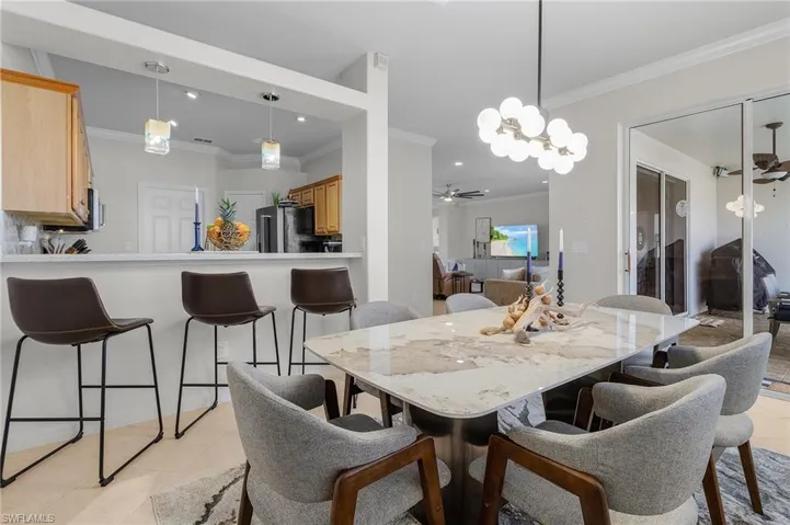 Dining room with ornamental molding, light tile patterned floors, and a chandelier