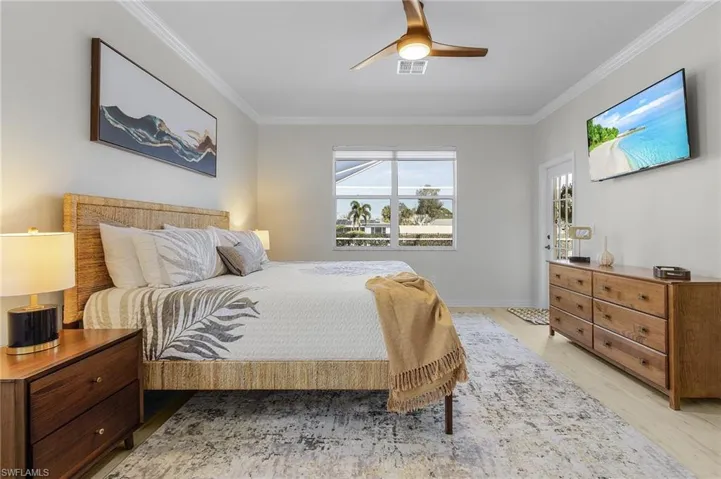 Bedroom with ceiling fan, ornamental molding, and light hardwood / wood-style floors