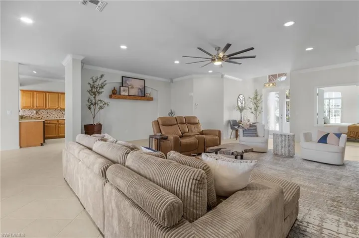 Tiled living room featuring crown molding and ceiling fan