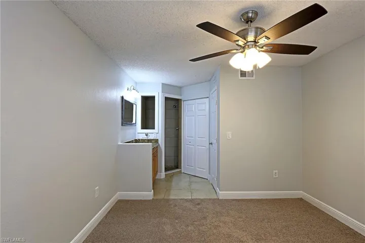 Unfurnished room featuring a textured ceiling, light colored carpet, and ceiling fan