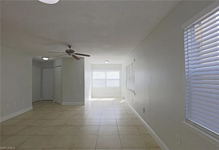 Spare room with a textured ceiling, light tile patterned flooring, and a ceiling fan