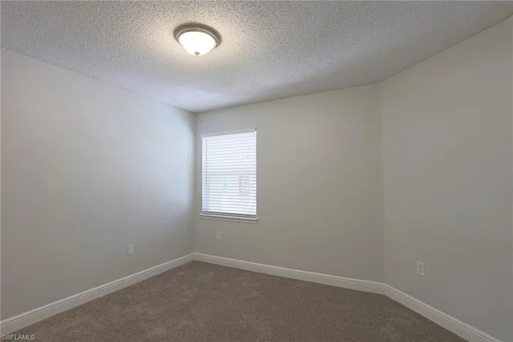Unfurnished room with dark carpet and a textured ceiling