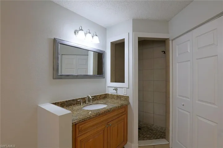 Full bath featuring vanity, a textured ceiling, and a shower stall
