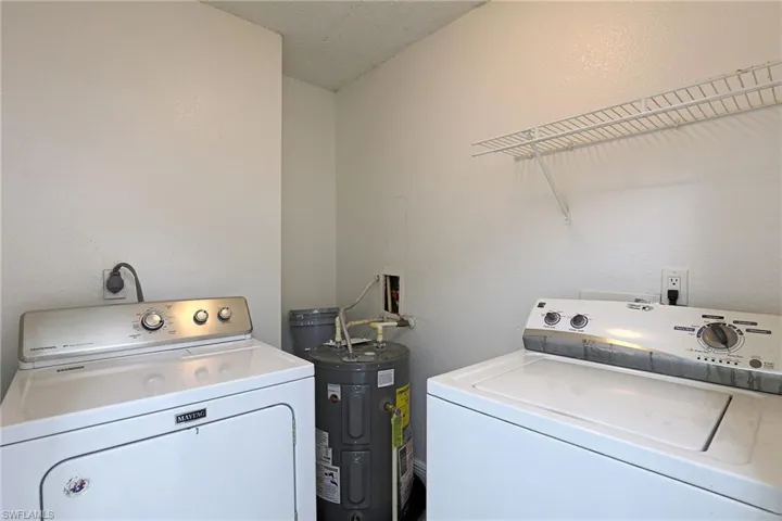 Laundry area featuring water heater, a textured wall, and separate washer and dryer