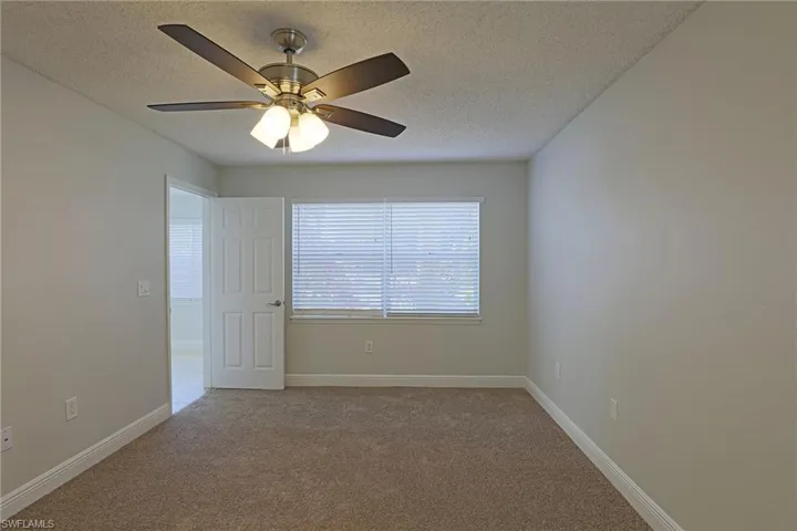 Spare room featuring a textured ceiling, carpet floors, and a ceiling fan