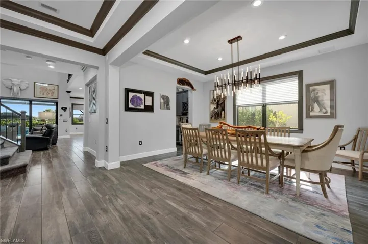 Dining space with a wealth of natural light, dark wood-type flooring, and a notable chandelier