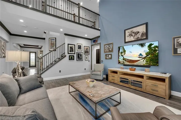 Living room featuring a towering ceiling, dark hardwood / wood-style flooring, and ornamental molding