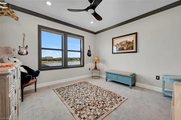 Living area featuring a water view, crown molding, ceiling fan, and light colored carpet