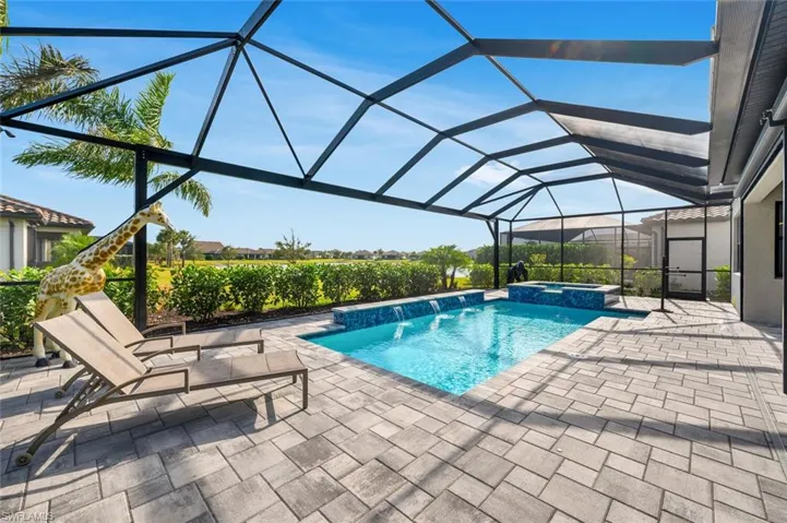 View of swimming pool featuring an in ground hot tub, pool water feature, a patio, and glass enclosure