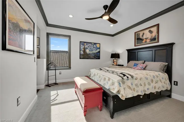 Carpeted bedroom with ceiling fan and ornamental molding