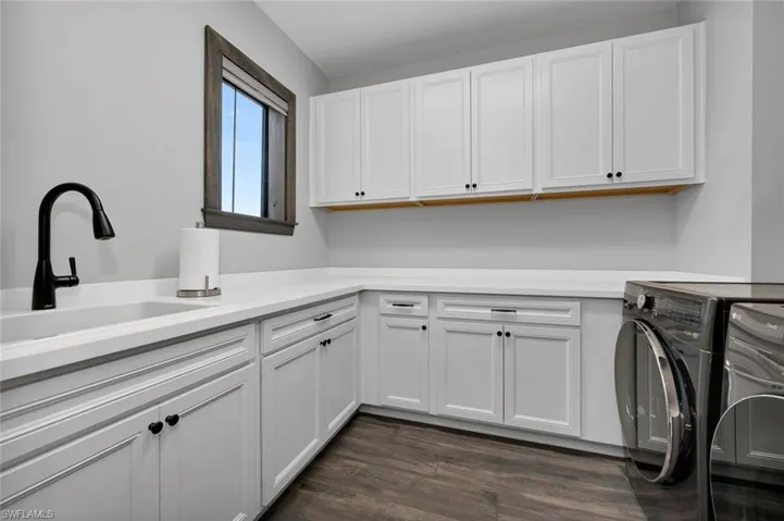 Clothes washing area featuring washer and dryer, dark hardwood / wood-style floors, cabinets, and sink