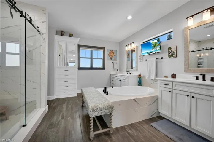 Bathroom featuring wood-type flooring, vanity, and a tile shower