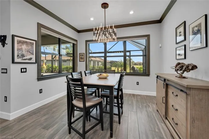 Dining room with a notable chandelier, crown molding, and dark wood-type flooring