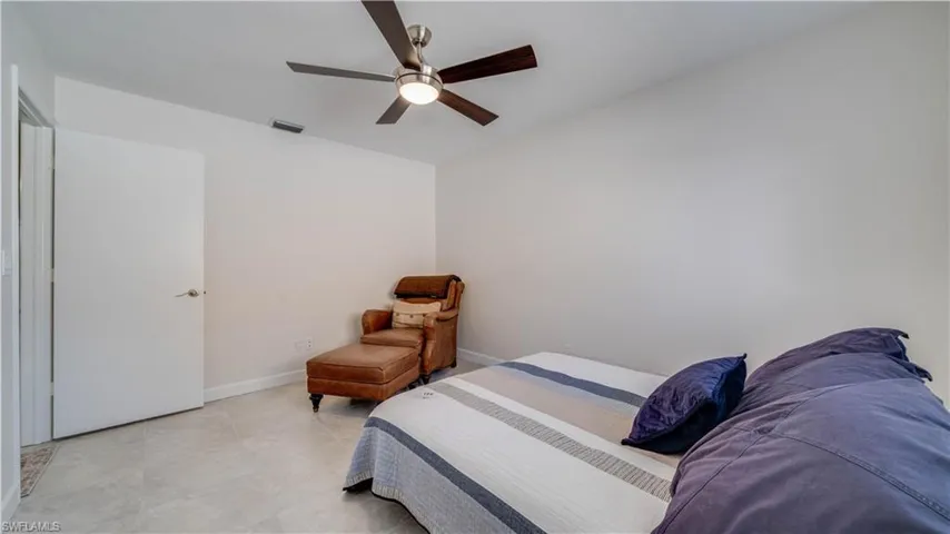 Guest Bedroom floors are tiled and has a modern fan.