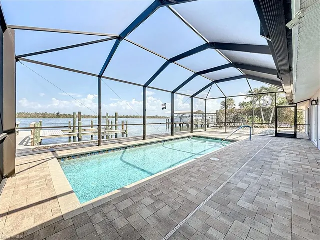 Outdoor pool with a sunroom, a patio, a lanai, a dock, and boat lift