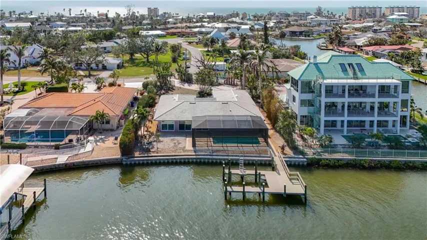 Aerial from Estero Bay looking at maintained property at 5650 Williams with boat dock, seawall, and pool.