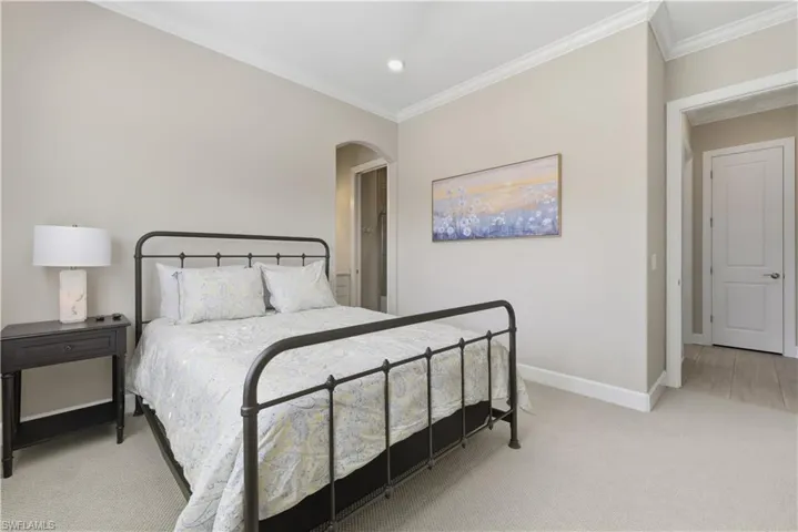 Bedroom featuring light carpet, crown molding, arched walkways, and recessed lighting