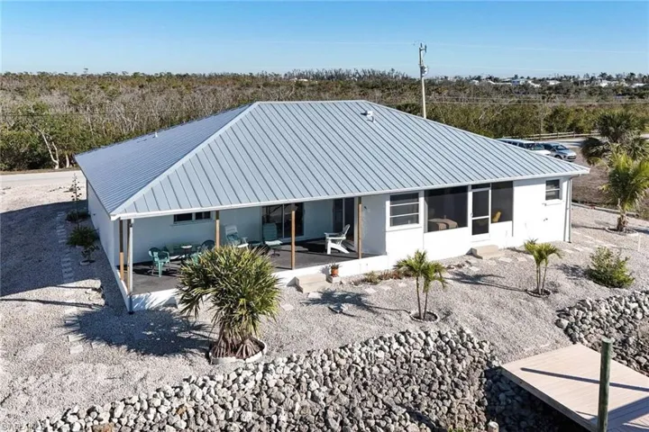 Back of house featuring a metal roof, a patio, a sunroom, and stucco siding