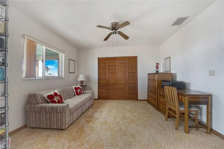 Carpeted living area with a ceiling fan and an office area