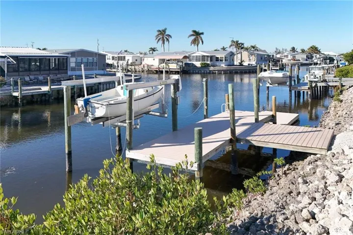 Dock area featuring boat lift, a water view, and a residential view