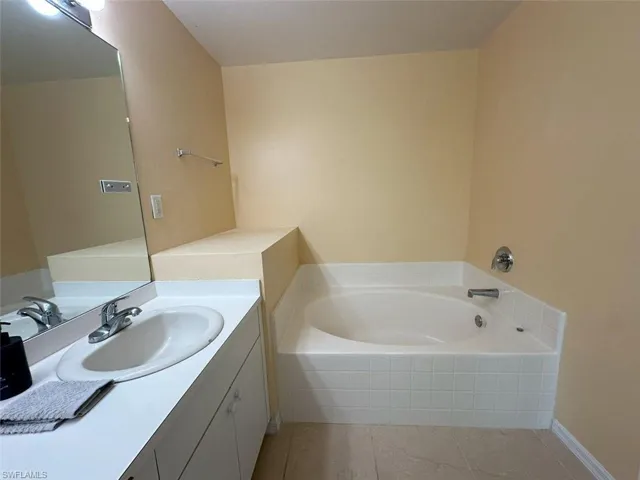 Bathroom with a relaxing tiled tub, tile patterned floors, and vanity
