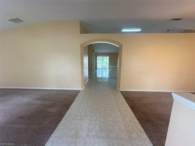Carpeted empty room with lofted ceiling