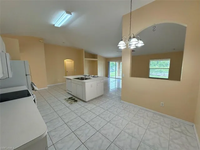 Kitchen featuring light tile patterned flooring, white cabinetry, an inviting chandelier, and pendant lighting