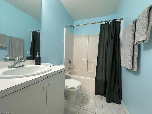 Full bathroom with vanity, tile patterned flooring, toilet, and shower / bath combination with curtain
