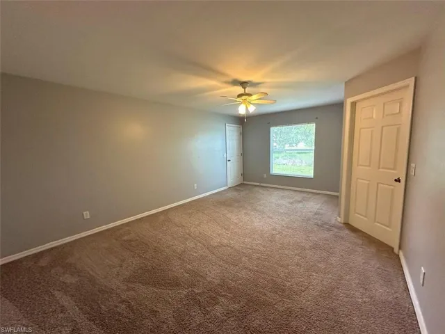 Carpeted spare room featuring ceiling fan
