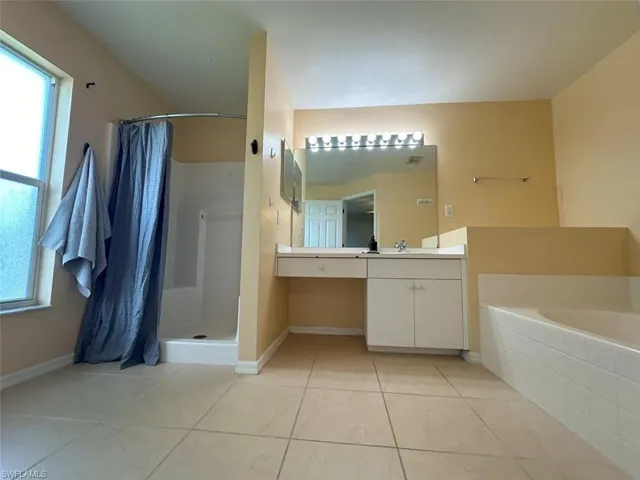 Bathroom with tile patterned floors, vanity, shower with separate bathtub, and a healthy amount of sunlight