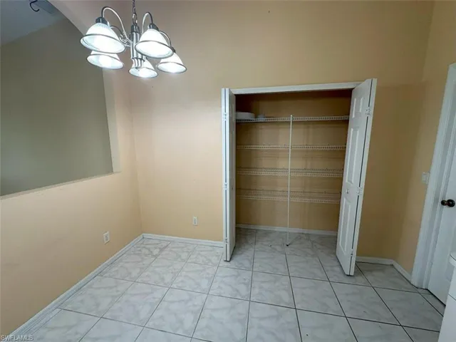 Unfurnished bedroom with light tile patterned flooring, a closet, and a notable chandelier