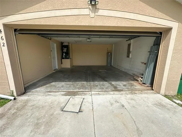 Garage featuring heating unit, water heater, and electric panel