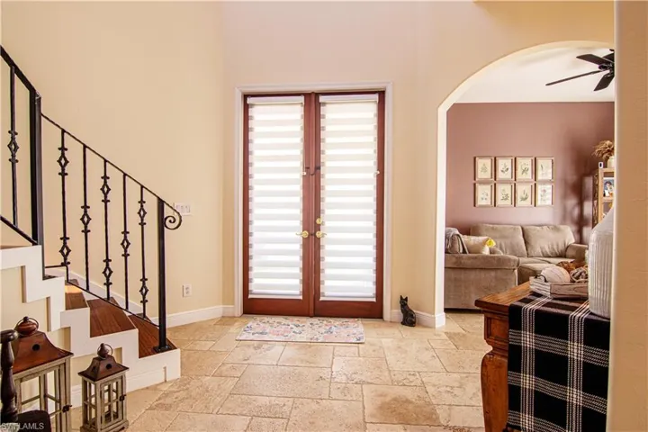 Step into a beautiful bright foyer featuring travertine floors leading to arched walkways.