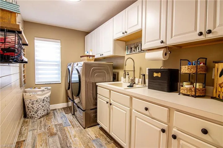 Laundry area features lots of cabinet's for storage, along with a newer high end washer & dryer set and a functional tub style sink.