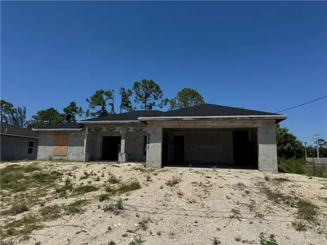 View of front facade featuring concrete block siding, an attached garage, and dirt driveway