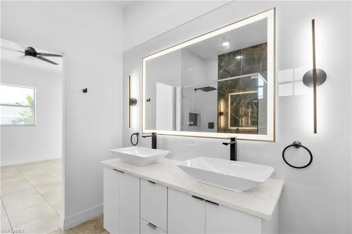 Bathroom featuring an enclosed shower, double vanity, and ceiling fan