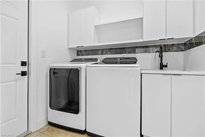 Laundry area with cabinet space, separate washer and dryer, and light tile patterned floors