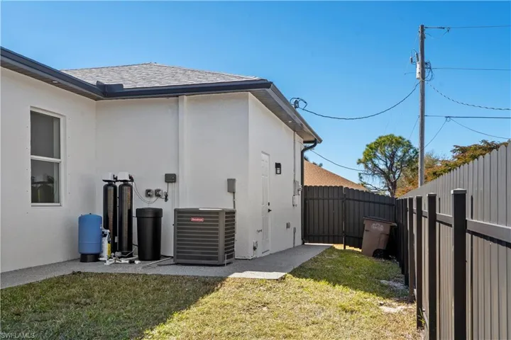 View of side of property with stucco siding, a fenced backyard, and roof with shingles