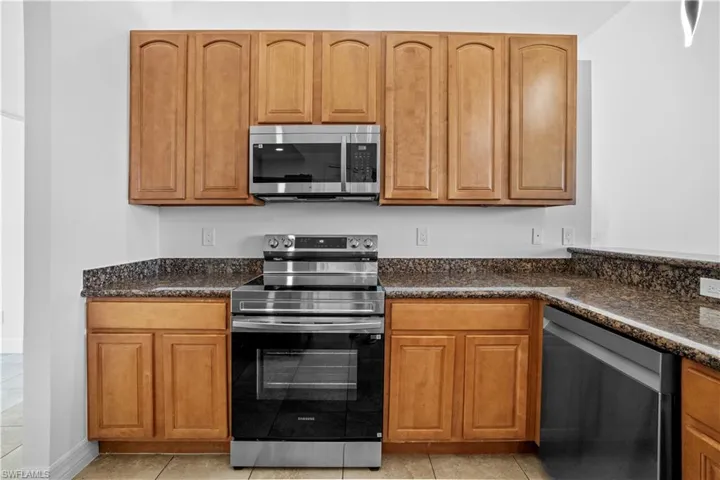 Kitchen featuring stainless steel appliances, dark stone countertops, and wood finish cabinets