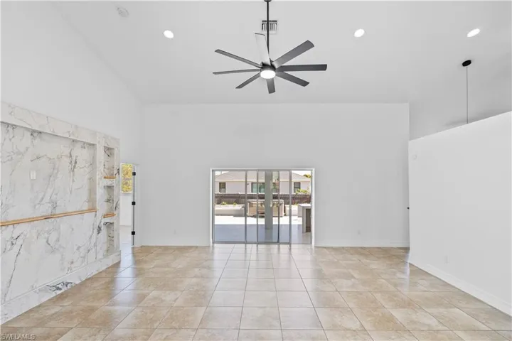 Empty room with recessed lighting, a ceiling fan, a high ceiling, and light tile patterned floors