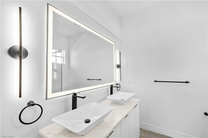 Full bathroom with double vanity and baseboards