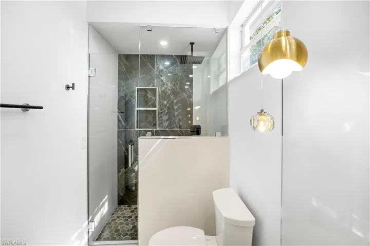 Full bath with a marble finish shower and recessed lighting