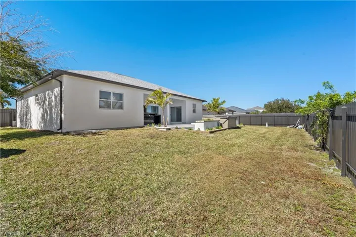 Rear view of house featuring a fenced backyard, stucco siding, and a patio area