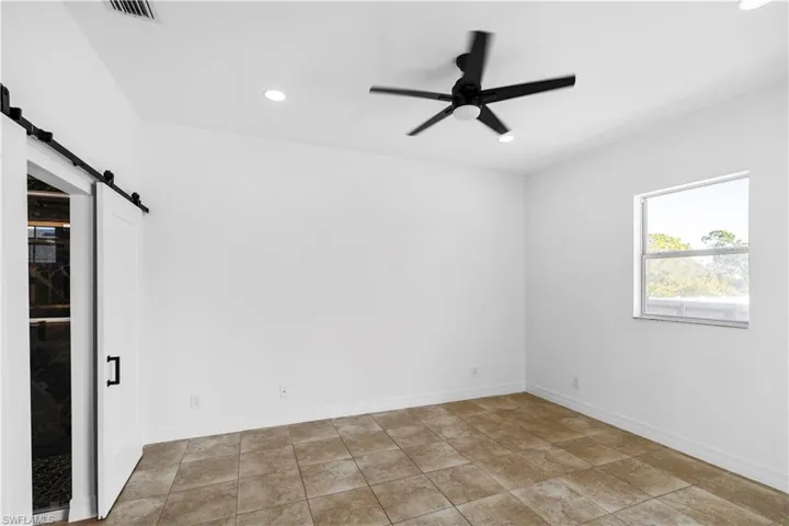 Empty room featuring a barn door, a ceiling fan, and recessed lighting