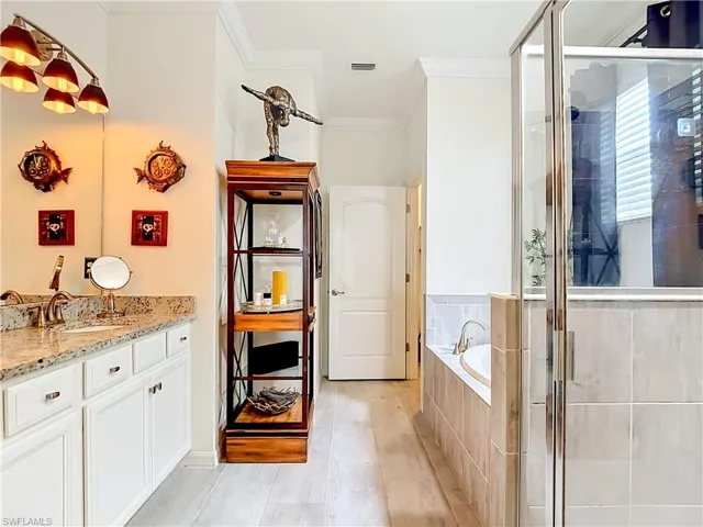 Bathroom featuring a double vanity with granite countertop, white cabinetry, a built-in soaking tub with tile surround, a glass-enclosed shower, and wood-finish flooring